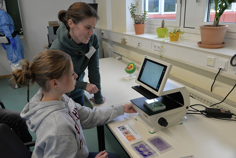 Dr. Nadine Krüger zeigt, wie Viren unter dem Fluoreszenzmikroskop aussehen. Foto: Katharina Diederich