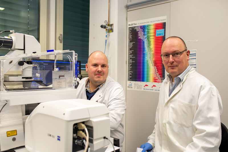 Zwei Männer sitzen hinter eine, Mikroskop in einem Labor.