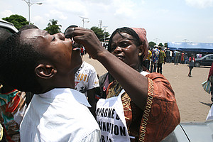 Das Foto zeigt eine Frau, die einem Mann eine Schluckimpfung verabreicht.